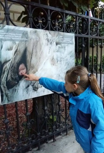 Fetiță arătând cu degetul spreo fotografie în care este un bebeluș