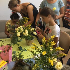parinți ajută copiii în scaun rulant să poata atinge florile dintr-un vas
