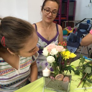 mama si fiica privesc un aranjament floral