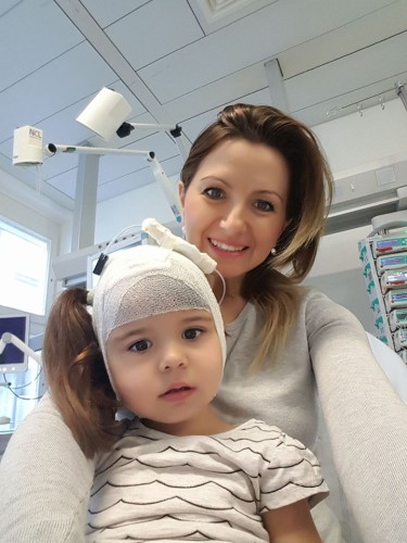 copil în spital, în brațele mamei, are capul bandajat