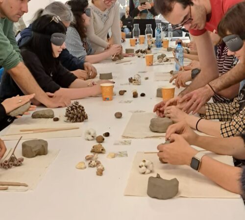 participanți la atelierul de ceramică pe nevăzute, ținut de asociația Amais. Unii dintre ei sunt nevăzători, alții poartă ochelari care sa le oprească vederea.
