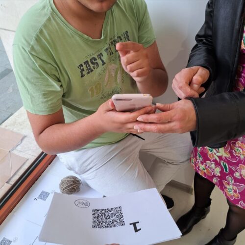 un tânăr este ajutat de mama sa să scaneze textele QR pentru a asculta textle de sală din expoziție.