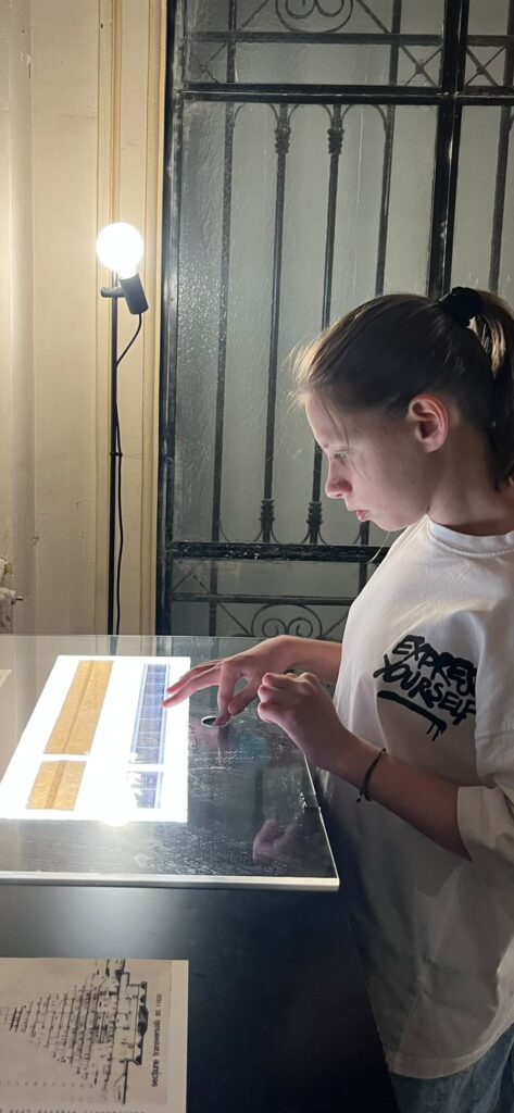 o fată tânără explorează expoziția muza la palat. Inspectează cu atenție o instalație luminoasă.